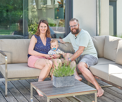 Familie Krusch sitzt glücklich auf der Terrassse in der Sonne