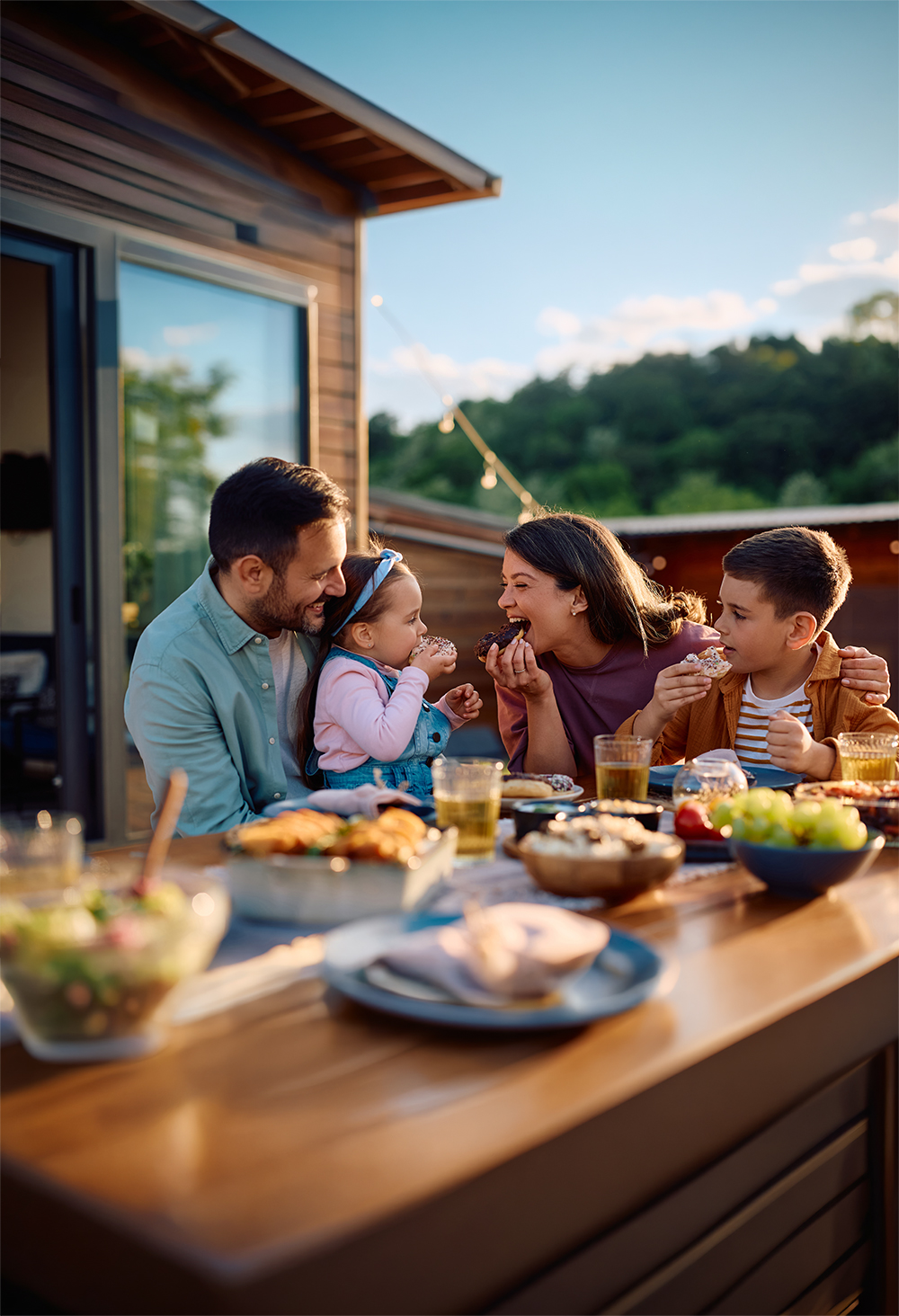 Eine junge Familie genießt das gemeinsame Essen auf der Terrasse des eigenen Kern-Haus